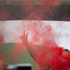 V Sign for Victory with Hand Fingers, Red Smoke and Flag in the Background