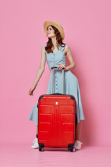 woman tourist in hat with red suitcase passenger lifestyle pink background