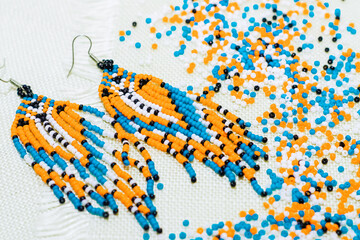 Ethnic decoration of an earring, visonane with a bead. Hand weaving beading, geometric pattern.