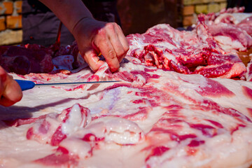 Butcher is cutting, processing fresh meat