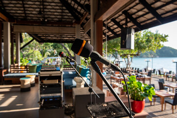 Microphone on a stand-up stage in the resort near the front of the beach on the island, blurred background.