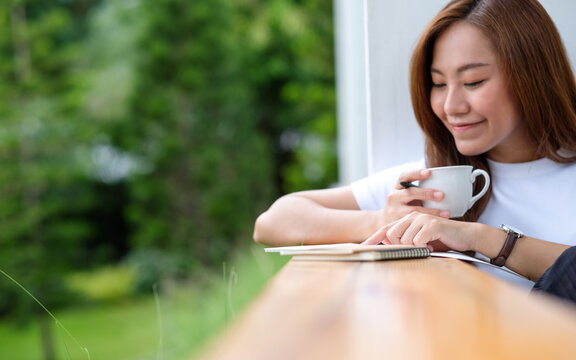 Closeup image of a beautiful young asian woman writing on a notebook in the outdoors