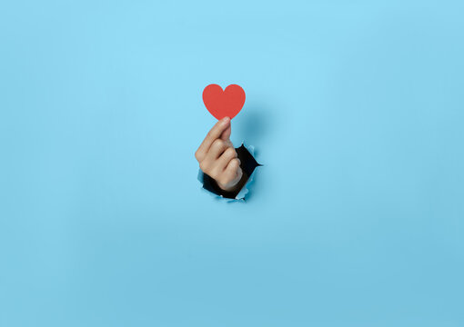 Woman hand holding heart on blue background.