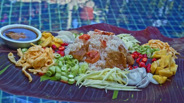 .Fried rice with shrimp paste served on banana leaves by the pool..red speckled banana leaves in the background..beautiful color of nature background. food and restaurant concept..