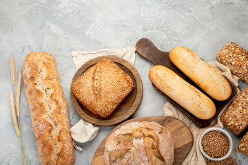 Various types of fresh baked bread on light gray background.