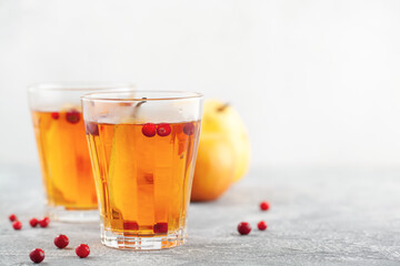 Winter or autumn hot healing tea with pear, orange, lingonberries, sea buckthorn and spices in glass cup.