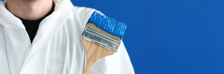Smiling master house painter holds paintbrush with blue paint