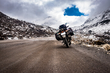 biker loaded bike at remote isolated road with snow cap mountains at background