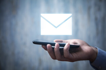 Male hand holding smartphone with email icon.