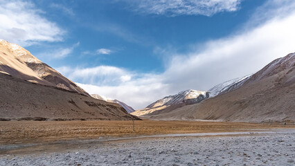 Beautiful panoramic view of a mountainside lit at the sunset period and also including of a snow found high up in the mountain peaks.