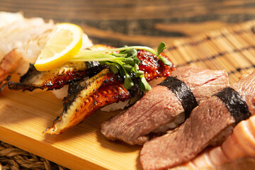 Eel sushi and beef sushi on a bamboo plate 