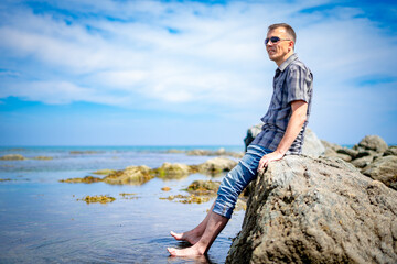 a man on a rocky seashore looks into the distance
