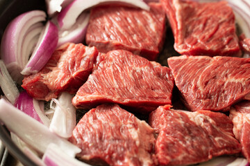 Raw beef and onions in a cast iron pan