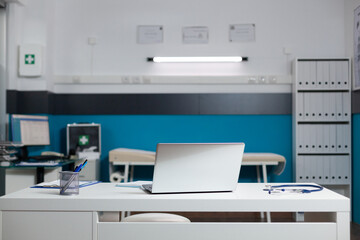 Empty doctors office room with medical equipment used for appointments with patients at clinic. Nobody in healthcare cabinet indoors, deisgned for professional consultation and medic