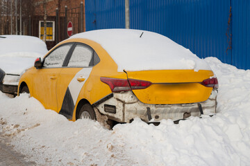 Taxis are parked on the roadside in winter. Snow-covered cars.