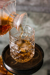 Pouring whiskey in glass with ice. Dammed glass with strong alcoholic drink.