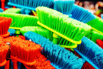 Plastic brushes for cleaning premises. Assortment of multi-colored brooms in the store. Close-up