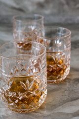 Three crystal glasses of whiskey on a wooden table.