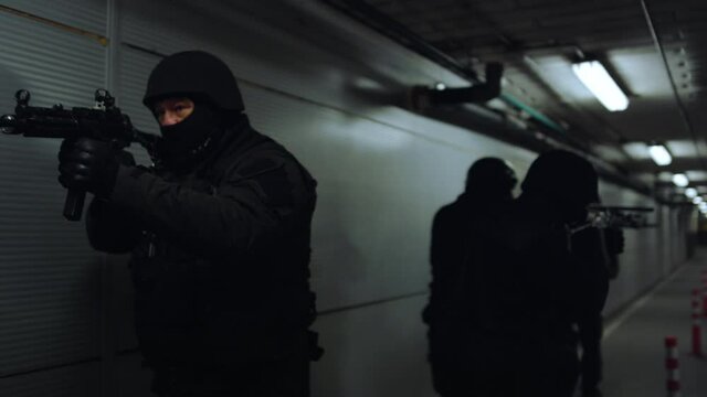 SWAT team walking in dark corridor. Special forces group pointing weapons