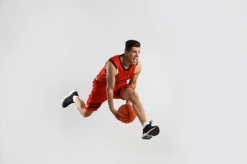 Fototapeta na wymiar Professional sportsman playing basketball on grey background