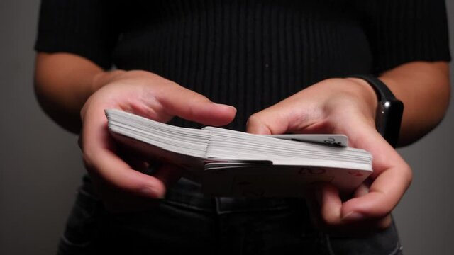 Caucasian woman shuffles poker cards in the air, professional player, close-up