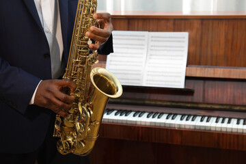 Naklejka premium African-American man playing saxophone indoors, closeup with space for text. Talented musician