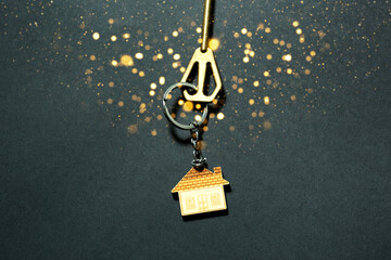 The key to the house with gold sequins and glow on a black background. Building, design, project,...