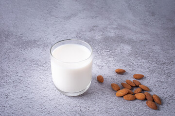 Glass of Almond milk and almond seeds isolated on brown background. Healthy drinks concept.