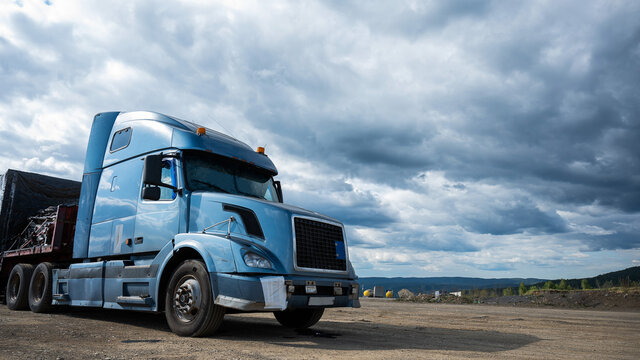 A parked truck with a blue cab against a gray sky