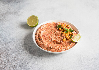 Roasted red pepper hummus garnish with mint and lime. Mashed chickpeas with red bell pepper, lime and mint. Vegetarian snack.