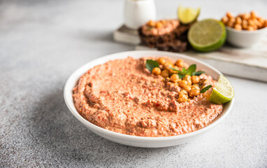 Roasted red pepper hummus garnish with mint and lime. Mashed chickpeas with red bell pepper, lime and mint. Vegetarian snack.