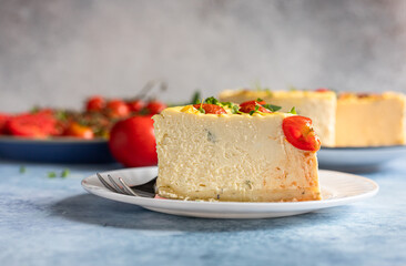 Piece of savoury tomato cheesecake with herbs decorated mint, blue concrete background.