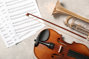 Violin, trumpet and note sheets on light grey background, flat lay. Musical instruments