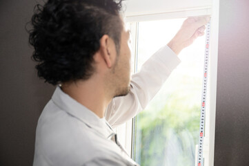 窓枠を計るリフォーム業者のイメージ コピースペースあり