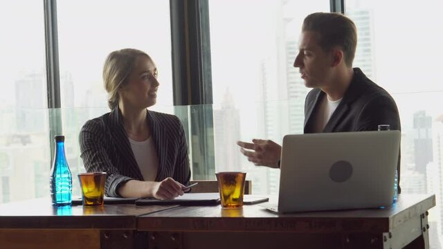 Young businessmen and business women sitting in meeting room discussing with information data on laptop computer near skyscraper office window . handshake to deal . agreement