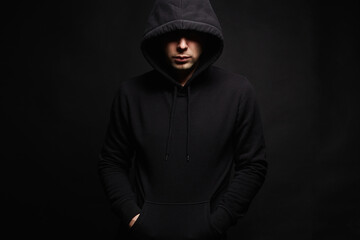 Man in Black Hood in dark studio. Boy in a hooded sweatshirt