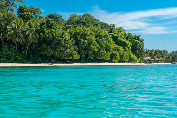 Fototapeta na wymiar Coastline of the Togian Island Batudaka in the Gulf of Tomini in Sulawesi. Guesthouses at the Island beach. It's a paradise for divers and snorkelers and offers an incredible diversity of species