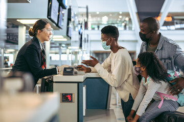 African family at airport check-in desk with face masks