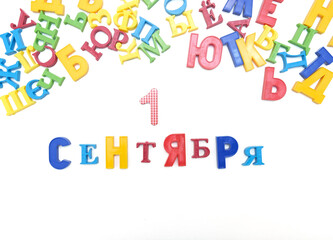 Inscription in Russian September 1 and colorful of randomly placed letters of the Russian alphabet, white background