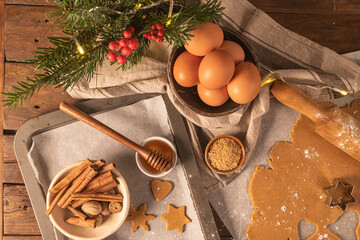 Making christmas gingerbread cookies. Raw dough in shape of gingerbread man, christmas tree, star, snowflakes on paper on tray on rustic table with rolling pin. Preparing for baking