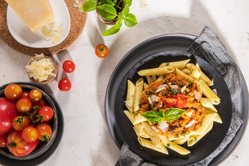 Tasty appetizing classic italian penne pasta with vegetarian lentil bolognese sauce, cheese parmesan and basil on plate on light table. Healthy eating concept.