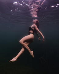 Fototapeta premium girl dives from the depths of the lake against the background of darkness