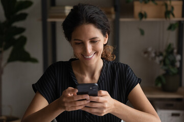 Close up smiling woman using smartphone, browsing mobile device apps, chatting with friends in...