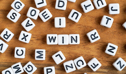 Small white and black bead cubes on wooden board, letters in middle spell WIN