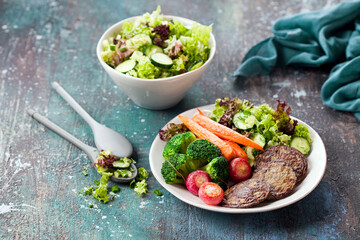 Liver cutlets or pancakes with fried radishes, carrots, broccoli and fresh green salad, selective focus