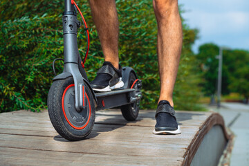 Obraz premium Close Up Of Man Riding Electric Kick Scooter At Beautiful Park Landscape
