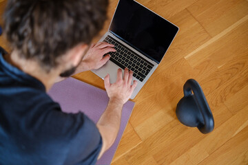 Man using a laptop to exercise at home with an online class. Top view.