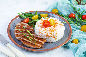 Rice with grilled pork meat, tomatoes and green herbs on white background