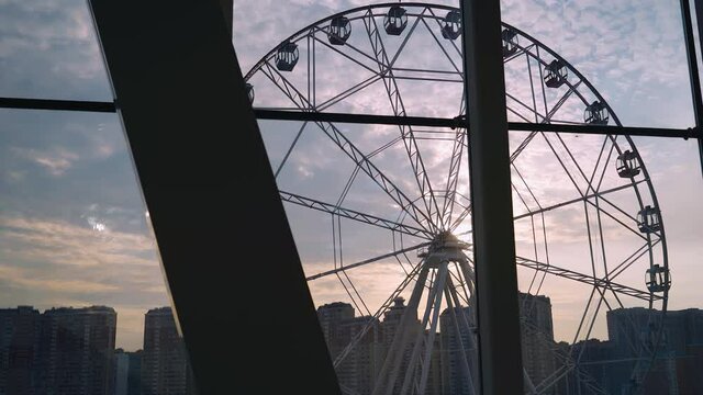 Cool shots of the ferris wheel in the city at sunset. Shooting in motion through the glass.