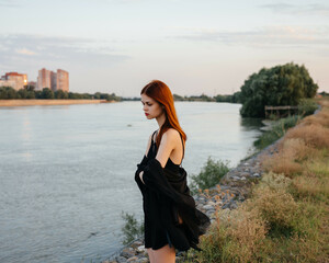 pretty red-haired woman in black dress outdoors posing fresh air
